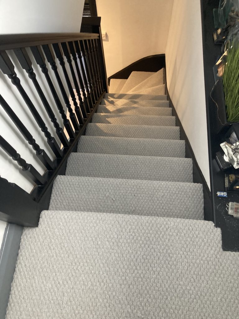 Light carpet fitted on staircase with black and white bannisters
