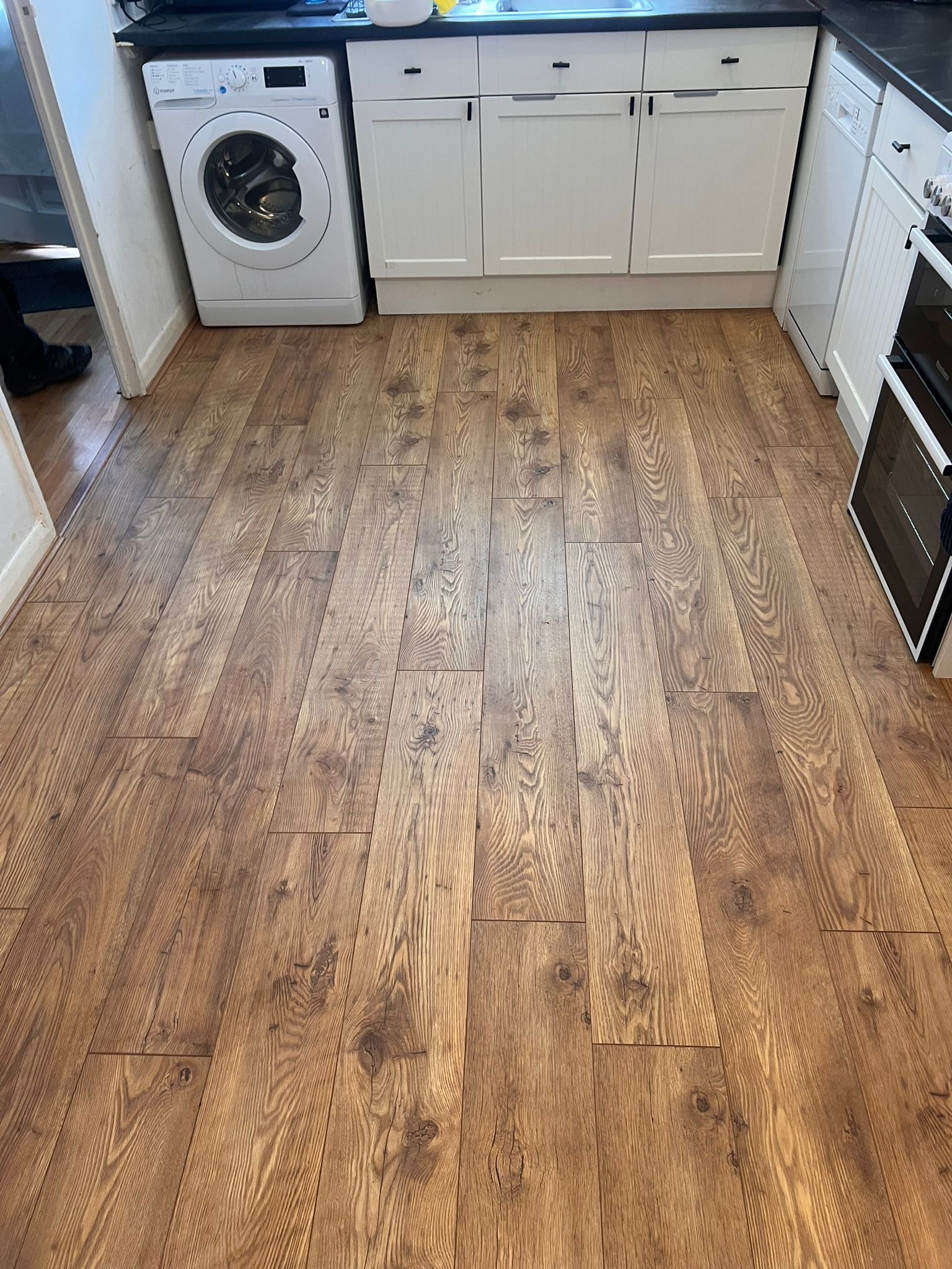 Wood effect laminate flooring professionally fitted in a kitchen by Strictly Floors